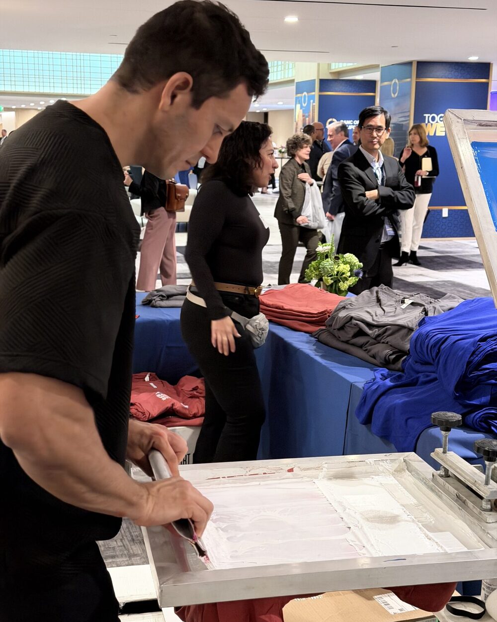 Staffer pulling a finished shirt from the press