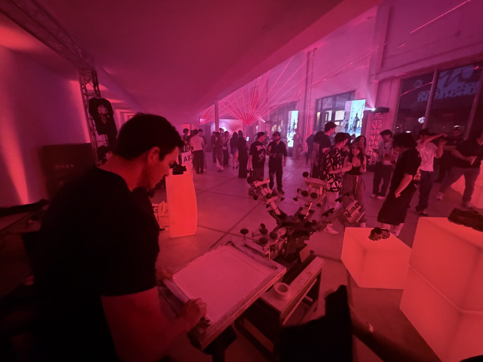 Night party crowd around a glowing live printing booth